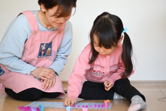 女の子に教える保育士